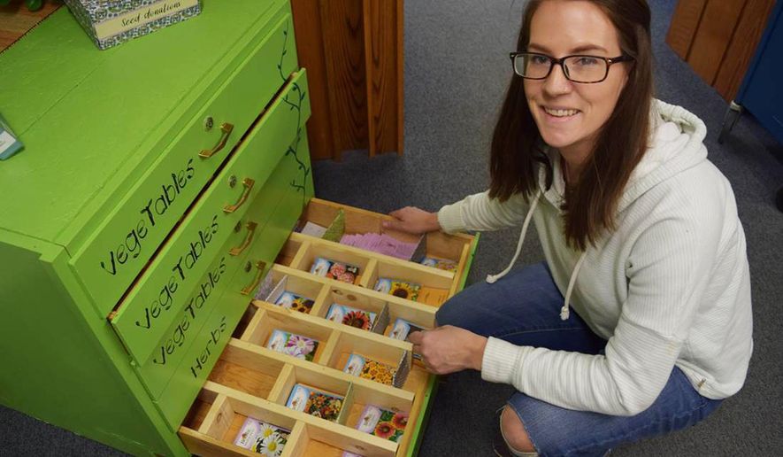 In this March 30, 2018 photo, Suzanne "Suzi" Catharine, the Livingston-Park County Public Library's outreach services librarian, inspects packets in the new seed library, in Livingston, Mont. Seed libraries encourage local food production, plant diversity and the promulgation of seeds that do well in a particular environment. (Liz Kearney/Livingston Enterprise via AP)