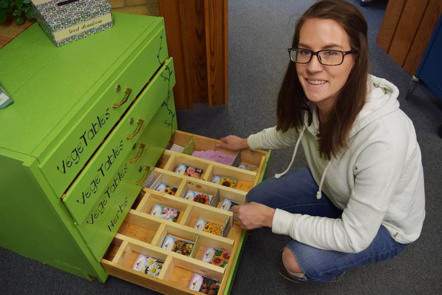 In this March 30, 2018 photo, Suzanne "Suzi" Catharine, the Livingston-Park County Public Library's outreach services librarian, inspects packets in the new seed library, in Livingston, Mont. Seed libraries encourage local food production, plant diversity and the promulgation of seeds that do well in a particular environment. (Liz Kearney/Livingston Enterprise via AP)