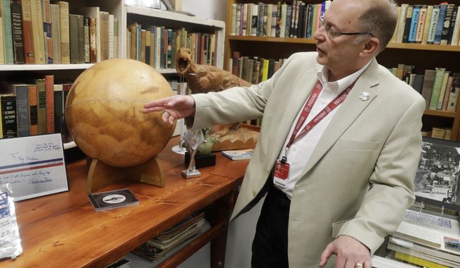 In this Thursday, April 12, 2018, photo, Center for Ray Bradbury Studies director Jonathan Eller points out the location of Gale Crater on the Mars globe, in Indianapolis. The globe presented to Ray Bradbury for his support of NASA&#x27;s Mariner 9 Mars orbital mission in 1971. (AP Photo/Darron Cummings)
