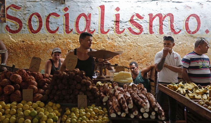 FILE - In this Dec. 20, 2014 file photo, workers stand behind their food stalls at a state-run market in Havana, Cuba. The average monthly state salary of $31 is so low that some workers often live on stolen goods and handouts from relatives overseas. (AP Photo/Desmond Boylan, File)