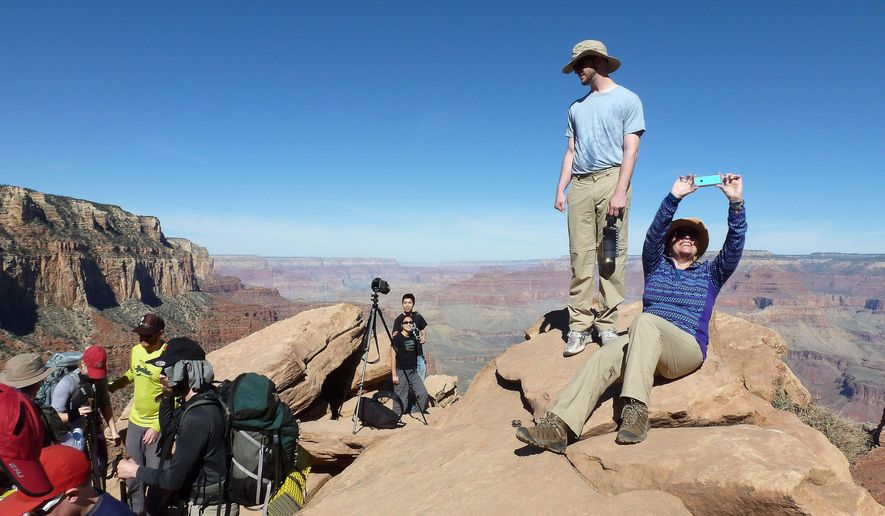 FILE - In this March 16, 2015, file photo, hikers stop and take photos along the Grand Canyon National Park&#x27;s South Kaibab trail. With diverse landscapes and abundant wildlife, America&#x27;s national parks are popular travel destinations. To save money on a trip, break out the camping gear and schedule your visit around a fee-free day or during off-peak time. (AP Photo/Anna Johnson, File)
