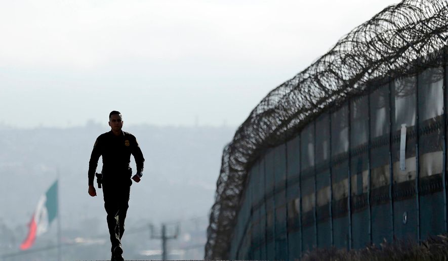 In this June 22, 2016, file photo, Border Patrol agent Eduardo Olmos walks near the secondary fence separating Tijuana, Mexico, background, and San Diego in San Diego. California has rejected the federal government&#x27;s initial plans for National Guard troops to the border because the work is considered too closely tied to immigration enforcement. (AP Photo/Gregory Bull, File)