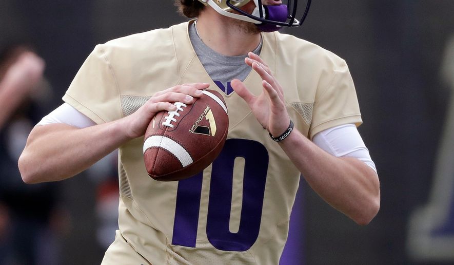FILE - In this March 28, 2018, file photo, Washington quarterback Jacob Eason readies a pass at the first practice of spring football for the NCAA college team, in Seattle. Eason knew his opportunity at Georgia was going to be limited if he remained with the Bulldogs. So he transferred home to Washington, even if it means he has to spend a year as a spectator. (AP Photo/Elaine Thompson, File)