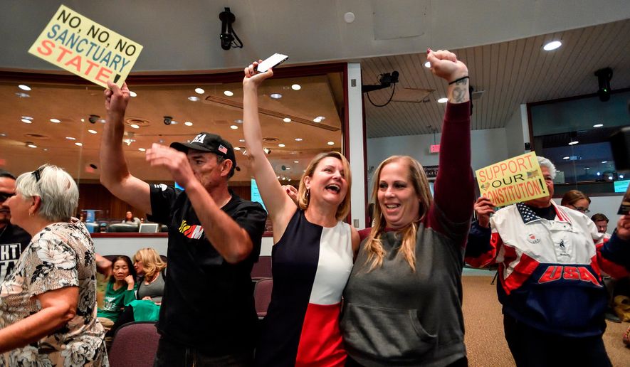 In this March 27, 2018, file photo, David Hernandez, left, Genevieve Peters, center, and Jennifer Martinez celebrate after the Orange County Board of Supervisors voted to join the U.S. Department of Justice lawsuit against the State of California&#39;s sanctuary cities law (SB54) during their meeting in Santa Ana, Calif. Leaders of California&#39;s second-largest county voted Tuesday, April 17, 2018, to officially support the Trump administration&#39;s lawsuit against the state&#39;s so-called sanctuary law that limits police cooperation with federal immigration agents. (Jeff Gritchen/The Orange County Register via AP, File)