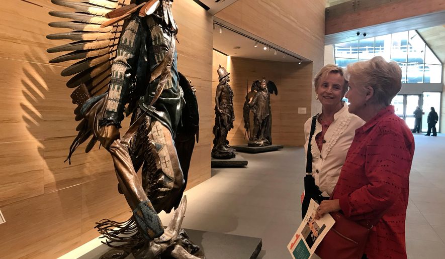 This April 11, 2018 photo shows visitors looking at an installation inside the James Museum of Western & Wildlife Art in St. Petersburg, Fla. When you think of Florida, the Grand Canyon's colored stone walls don't come to mind. Neither do cowboys, wolves or Native American silver-and-turquoise jewelry. In downtown St. Petersburg, all of those icons of the American West are on display in the new museum. (AP Photo/Tamara Lush)