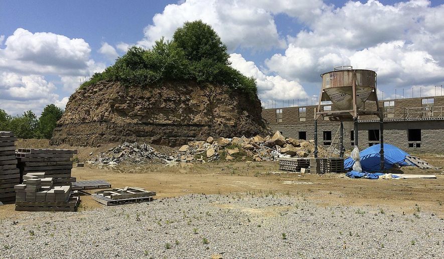 This undated photo, shows a large mound behind a motel in Franklin Township, Pa., that contains the Rhodes family cemetery. A group is suing the owners of a motel who started an excavation project in Pennsylvania that left their family cemetery a large mound of earth more than 25 feet high. The Observer-Reporter reports descendants of people buried in Rhodes Cemetery filed their lawsuit against Nikita Lodging Inc. April 4, 2018, saying they want the company to stabilize the cemetery, allow access to the area and restore the cemetery to its original condition. (Bob Niedbala/Observer-Reporter via AP)
