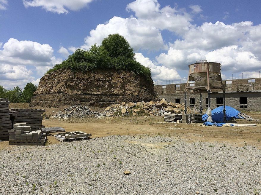 This undated photo, shows a large mound behind a motel in Franklin Township, Pa., that contains the Rhodes family cemetery. A group is suing the owners of a motel who started an excavation project in Pennsylvania that left their family cemetery a large mound of earth more than 25 feet high. The Observer-Reporter reports descendants of people buried in Rhodes Cemetery filed their lawsuit against Nikita Lodging Inc. April 4, 2018, saying they want the company to stabilize the cemetery, allow access to the area and restore the cemetery to its original condition. (Bob Niedbala/Observer-Reporter via AP)