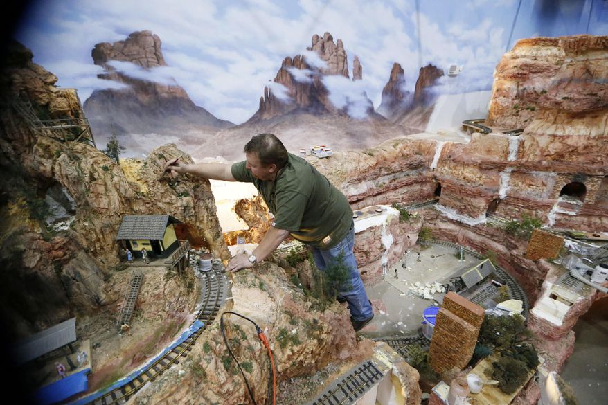 In this April 9, 2018 photo, Andy Wartman paints texture on one of the mountains in the Museum of the American Railroad at Frisco Discovery Center in Frisco, Texas. A grand opening in June is planned for the Museum of the American Railroad's new exhibit, aptly named TrainTopia. (Nathan Hunsinger/The Dallas Morning News via AP)
