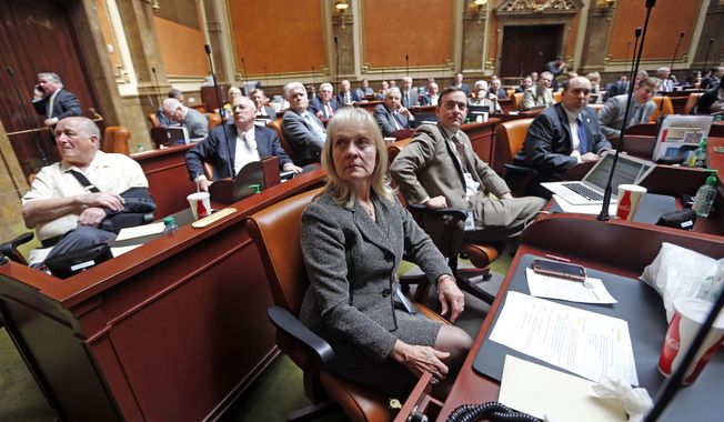 Rep. Christine F Watkins, center, R-Price, watches a vote on the House floor with other lawmakers during a special session at the Utah State Capitol Wednesday, April 18, 2018, in Salt Lake City. Utah lawmakers are overruling the governor on a pair of a pair of issues about the balance of power within the overwhelmingly GOP state, deepening an intra-party power struggle. Lawmakers used a special session on Wednesday to override Republican Gov. Gary Herbert's veto of two measures that he says encroach on his executive authority. (AP Photo/Rick Bowmer)