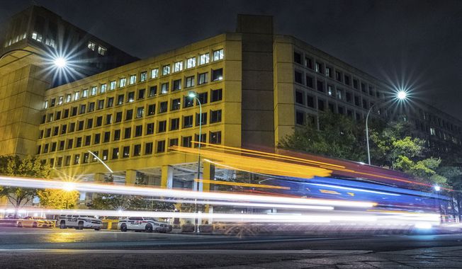 FILE - In this Nov. 1, 2017, file photo, traffic along Pennsylvania Avenue in Washington streaks past the Federal Bureau of Investigation headquarters building. In the two weeks since the #Releasethememo hashtag first sprouted on Twitter, a secret congressional report on the Russia investigation has gone from an obscure, classified document to a bitter point of conflict between not only Democrats and Republicans but also the White House and the FBI. (AP Photo/J. David Ake)