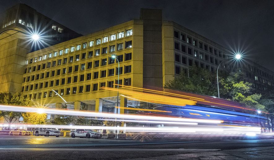 FILE - In this Nov. 1, 2017, file photo, traffic along Pennsylvania Avenue in Washington streaks past the Federal Bureau of Investigation headquarters building. In the two weeks since the #Releasethememo hashtag first sprouted on Twitter, a secret congressional report on the Russia investigation has gone from an obscure, classified document to a bitter point of conflict between not only Democrats and Republicans but also the White House and the FBI. (AP Photo/J. David Ake)