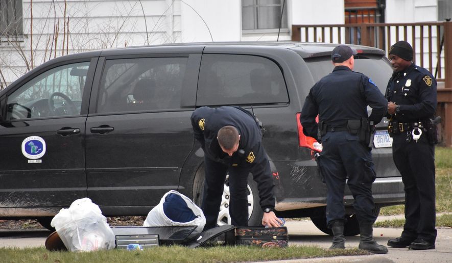In this Wednesday, April 18, 2018 photo, officers investigate after two infant children were allegedly left in a suitcase along West Pierson Pierson Road in Flint, Mich. Both children were taken to a local hospital and listed in good condition. A 26-year-old woman was taken into custody in connection with the incident. (Roberto Acosta/The Flint Journal-MLive.com via AP)