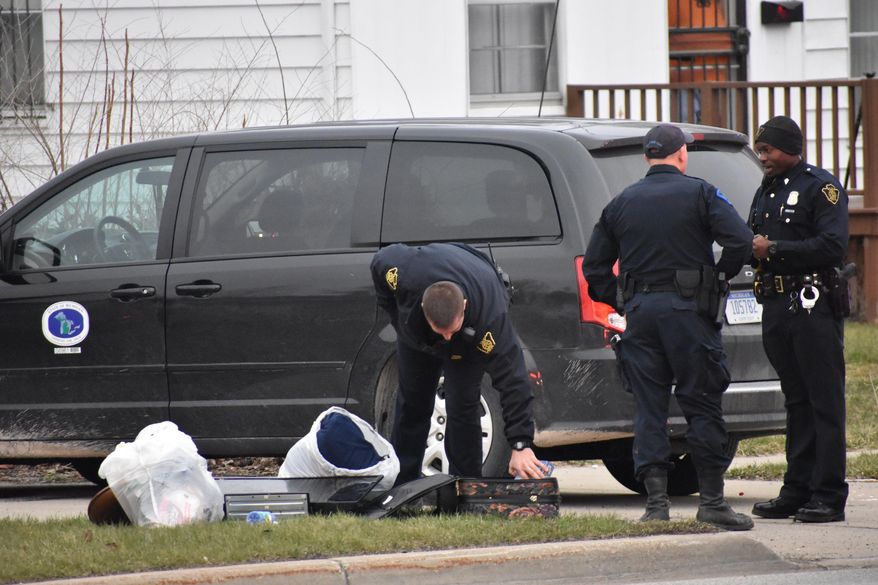 In this Wednesday, April 18, 2018 photo, officers investigate after two infant children were allegedly left in a suitcase along West Pierson Pierson Road in Flint, Mich. Both children were taken to a local hospital and listed in good condition. A 26-year-old woman was taken into custody in connection with the incident. (Roberto Acosta/The Flint Journal-MLive.com via AP)