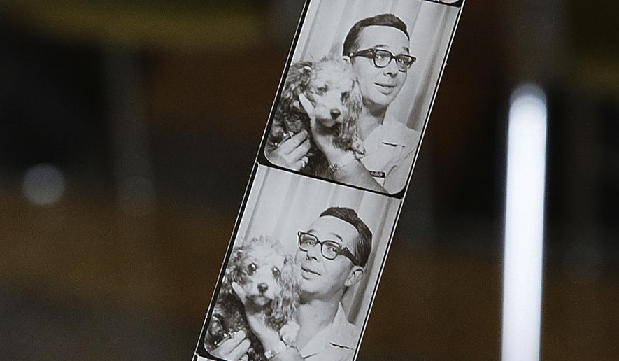 In this April 2, 2018 photo, Jon Chamlin holds a strip of photos of his relative former tavern  owner Ed Yanka, posing with his dog, in Yanka&#x27;s Tap on Fifth Street in Peru, Ill. Chamlin said Yanka would frequently sit for a picture in a photo booth to see how his toupee sat. Dogs were also a frequent subject of Yanka&#x27;s artwork that covers the walls of the tavern. Chamlin restored his great-uncle Ed&#x27;s tavern and has many works by Yanka on display. (Scott Anderson /NewsTribune via AP)