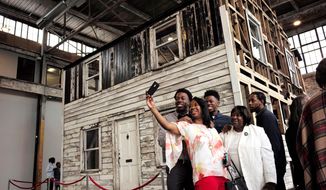 File — In this Sunday, April 1, 2018 file photo Cheryl Galloway, of Providence, R.I., front, uses a mobile phone to take a photo with family members in front of the rebuilt house of Rosa Parks at the WaterFire Arts Center, in Providence. The house will be displayed in Rhode Island for at least a month because several groups, including NAACP Providence, have provided money. The house was supposed to be the centerpiece of a weeks long exhibition this spring at Brown University, which the Ivy league school abruptly canceled. Rosa Parks moved to the house in Detroit in 1957, two years after refusing to give up her bus seat. (AP Photo/Steven Senne, File)