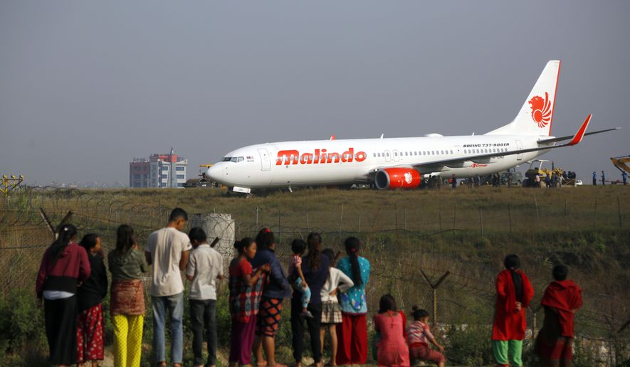 People watch a Malindo Air passenger plane after it skidded to the grassy area at the end of runway in Tribhuwan International Airport in Kathmandu, Nepal, Friday, April 20, 2018. The Nepal&#x27;s only international airport remained closed Friday after the passenger plane attempting to take off skidded off the runway. No one was injured. (AP Photo/Niranjan Shrestha)