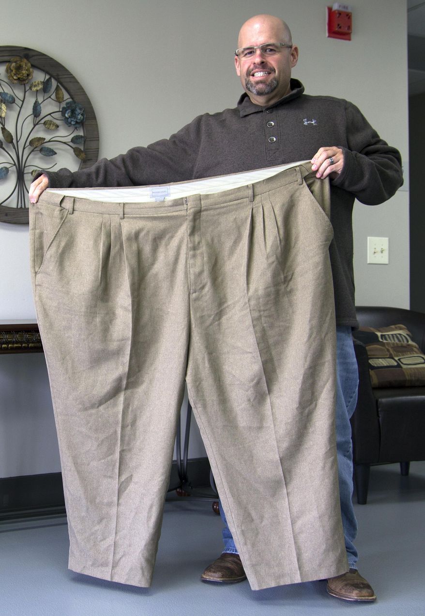 Pastor Jeremy Atwood holds a pair of his old pants in the lobby of Immanuel Baptist Church in Glasgow, Ky., on April 10, 2017. Atwood wore the pants when he weighed 491 pounds. The Glasgow pastor has lost 240 pounds over the past two years on a quest to restore his physical and spiritual health. (Roger Alford/Kentucky Today via AP)