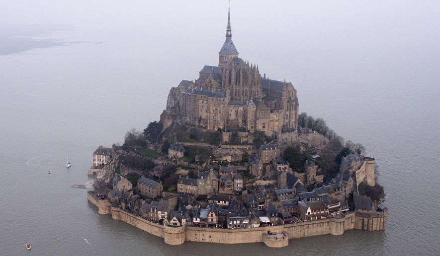 FILE - In this March 21, 2015 file photo, a high tide submerges a narrow causeway leading to the Mont Saint-Michel, on France&#x27;s northern coast. Authorities are evacuating tourists and others from the Mont-Saint-Michel abbey and monument in western France on Sunday April 22, 2018, after a visitor apparently threatened to attack security services. (AP Photo) FRANCE OUT