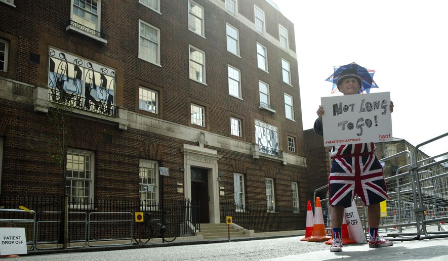FILE - In this Friday, April 24, 2015 file photo, Terry Hutt poses for the media with a sign that reads &#x27;Not Long to Go&#x27; as he waits with other royal fans, outside the Lindo wing at St Mary&#x27;s Hospital in London.  Kensington Palace says Prince William&#x27;s wife, the Duchess of Cambridge has entered a London hospital to give birth to the couple&#x27;s third child. The former Kate Middleton traveled by car on Monday, April 23, 2018 to the private Lindo Wing of St. Mary&#x27;s Hospital in central London. The palace says she was in &amp;quot;the early stages of labor.&amp;quot; (AP Photo/Alastair Grant, File)