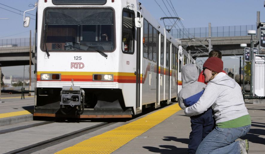 FILE - In this Nov. 19, 2006 file photo, Jill Cooper, right, holds her 3-year-old son, Wyatt, as a Regional Transportation District light rail train arrives at the Broadway station in Denver. The Colorado Supreme Court on Monday, April 23, 2018 upheld the legality of sales taxes the district has been collecting since 2013 to supplement the transit service. (AP Photo/David Zalubowski, File)