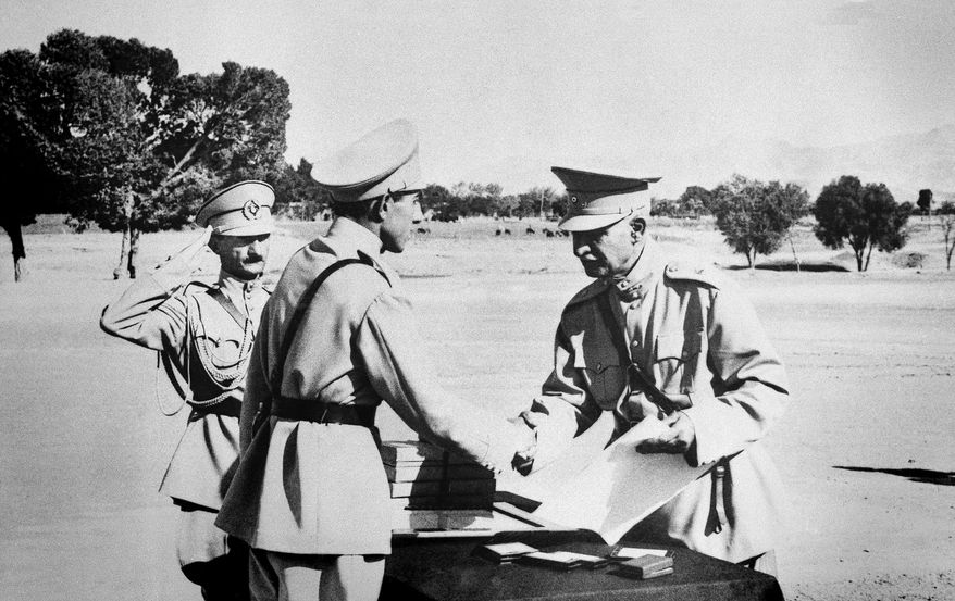 In this August 19, 1941 file photo, Reza Shah Pahlavi, hands second son, Ali Reza, commission as officer at graduation exercises at Iran's "West Point" in Tehran, Iran prior to Anglo-Russian action. The discovery in Iran of a mummified body near the site of a former royal mausoleum has raised speculation it could be the remains of the late Reza Shah Pahlavi, founder of the Pahlavi dynasty. (AP Photo, File)