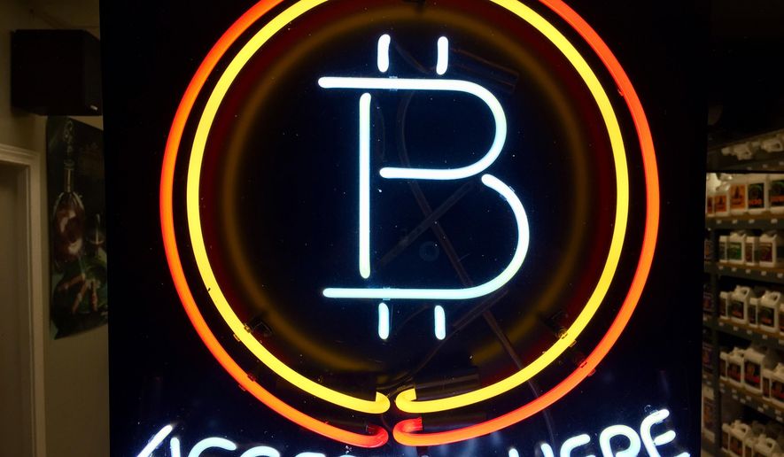 FILE - In this Feb. 7, 2018 File, photo, a neon sign hanging in the window of Healthy Harvest Indoor Gardening in Hillsboro, Ore., shows that the business accepts bitcoin as payment. The Wisconsin Ethics Commission is considering a policy guiding what to do about political contributions made in bitcoin and other cryptocurrencies. Bitcoin is gaining in popularity as a type of privately issued digital money. The Wisconsin Ethics Commission is holding a hearing Tuesday, April 24, 2018, in response to February request from the Libertarian Party of Wisconsin for public input and a policy on the use of campaigns accepting cryptocurrencies and making payments with them.(AP Photo/Gillian Flaccus File)