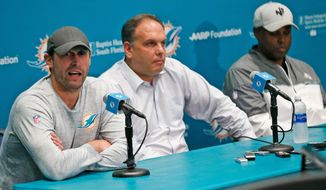 FILE - In this Jan. 3, 2018, file photo, Miami Dolphins head coach Adam Gase, left, answers a question during a news conference with Mike Tannenbaum, center, executive vice president of football operations, and Chris Grier, general manager, at the teams NFL football training camp in Davie, Fla. The tension between seeking an immediate draft dividend and investing for the long term is at the core of the Dolphins’ decision with the 11th overall pick.  The choice may show how much power Gase wields, but even if the other leaders in the organization yield to his preference, it’s uncertain which quarterback will land in Miami.   (AP Photo/Wilfredo Lee, File)