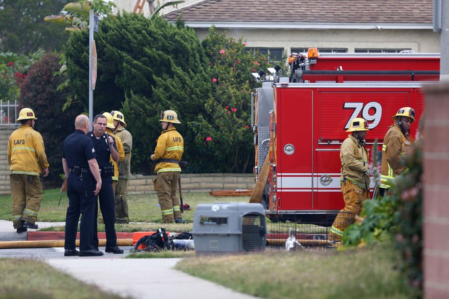 Los Angeles police and firefighters gather where authorities say a man fatally shot his mother after a house fire in the Gardena section of Los Angeles on Tuesday, April 24, 2018. (AP Photo/Daniel Bowyer)