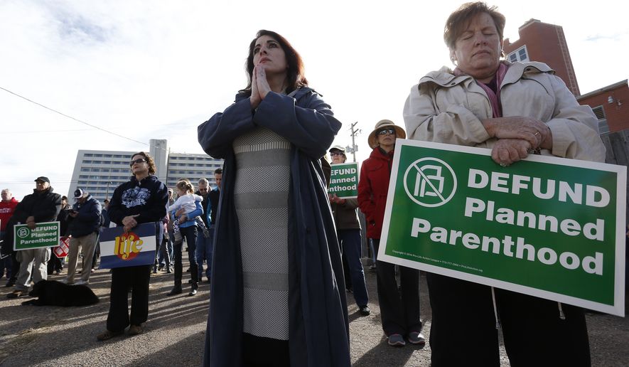 Participants in an anti-abortion rally hold signs and pray as they listen to a member of Christian clergy read from the Bible in front of Planned Parenthood of the Rocky Mountains in Denver on Feb. 11, 2017. (Associated Press) **FILE**