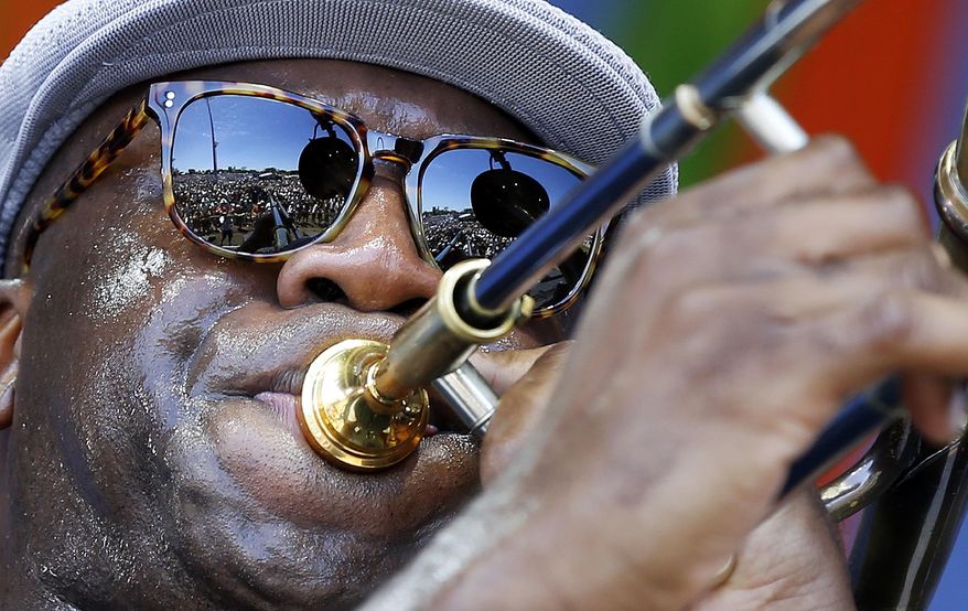 FILE - In this April 23, 2016 file photo, The crowd is reflected in the sunglasses of Big Sam, of Big Sam's Funky Nation, as he performs at the New Orleans Jazz and Heritage Festival in New Orleans. Music lovers are converging this week on the Crescent City for the festival, which takes place over two weekends starting on Friday, April 27, 2018, featuring out-of-town artists such as Rod Stewart and Sting, as well as performers from across New Orleans and Louisiana. (AP Photo/Gerald Herbert, File)