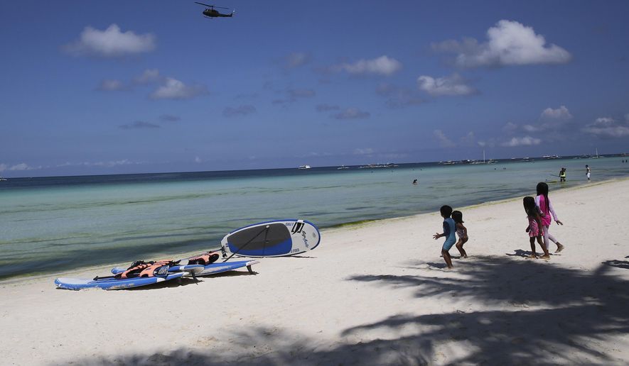 Children watch as a military helicopter passes by the country&#x27;s most famous beach resort island of Boracay, in central Aklan province, Philippines Wednesday, April 25, 2018, a day before the government implements its temporary closure. Thousands of workers will be affected when Boracay will be closed after Philippine President Rodrigo Duterte orders its closure on April 26 for up to six months after saying the waters off its famed white-sand beaches had become a &amp;quot;cesspool&amp;quot; due to overcrowding and development. (AP Photo/Aaron Favila)