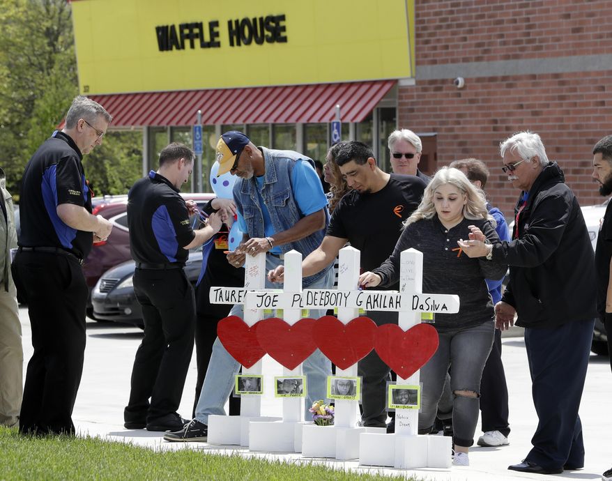 Family members of people killed at a Waffle House restaurant write messages on wooden crosses set up as a memorial Wednesday, April 25, 2018, in Nashville, Tenn. Four people were killed when a gunman opened fire at the restaurant Sunday. Members of the Waffle House management and staff joined the family members as the restaurant re-opened Wednesday. (AP Photo/Mark Humphrey)
