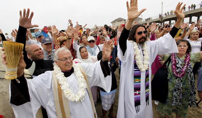FILE - In this Sunday, Oct. 3, 2010, file photo, Rev. Christian Mondor, left with Rev. Matt Munoz, center, offers a prayer to surfers during the Blessing of the Waves ceremony at the pier in Huntington Beach, Calif. Mondor, the "Surfing Padre" who wore a wetsuit under his clerical robe and presided over an annual Blessing of the Waves ceremony on a Southern California beach, died Wednesday, April 24, 2018, just two days before his 93rd birthday. (AP Photo/Richard Vogel, File)