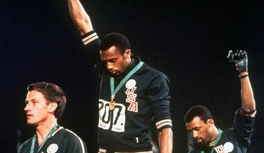 FILE - In this Oct. 16, 1968, file photo, Australian silver medalist Peter Norman, left, stands on the podium as Americans Tommie Smith, center, and John Carlos raise their gloved fists in a human rights protest. Australian Olympic Committee (AOC) awarded on Saturday, April 28, 2018, a posthumous Order of Merit to Norman. AOC President John Coates said that Norman&#39;s achievements as an athlete - his silver-medal winning time of 20.06 seconds at Mexico City remains an Australian record 50 years after he set the mark - were dwarfed by his support for the gold and bronze medalists who raised their gloved fists and bowed their heads during the American national anthem. (AP Photo, File)