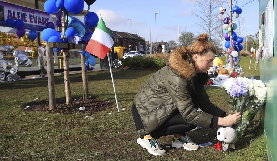 A woman leaves flowers outside Alder Hey Children&#39;s Hospital in Liverpool, England, following the death of 23-month-old, Alfie Evans, Saturday April 28, 2018. Alfie Evans, the sick British toddler whose parents won support from Pope Francis during a protracted legal battle over his treatment, died early Saturday. He was 23 months old. (Peter Byrne/PA via AP)