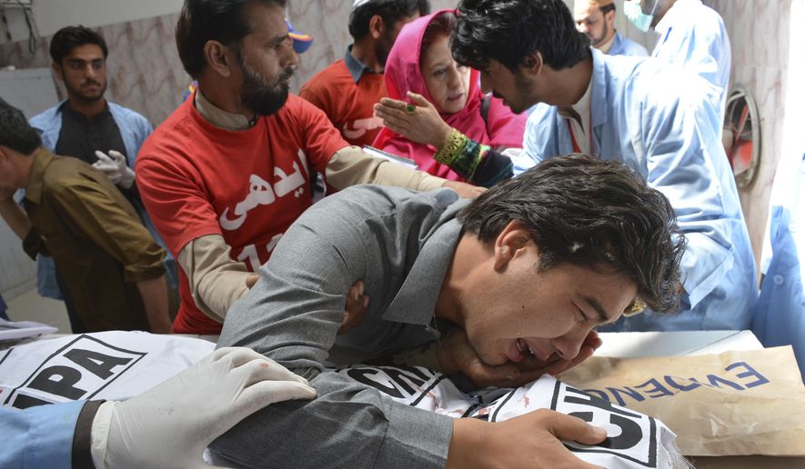 A Pakistani volunteer comforts a grief-stricken person from Shiite community, mourns over a body of his family member at a mortuary in Quetta, Pakistan, Saturday, April 28, 2018. Gunmen attacked an electronics shop and fatally shot two shopkeepers, both of them minority Hazara Shiites, said Mohammad Alam, area police officer. (AP Photo/Arshad Butt)