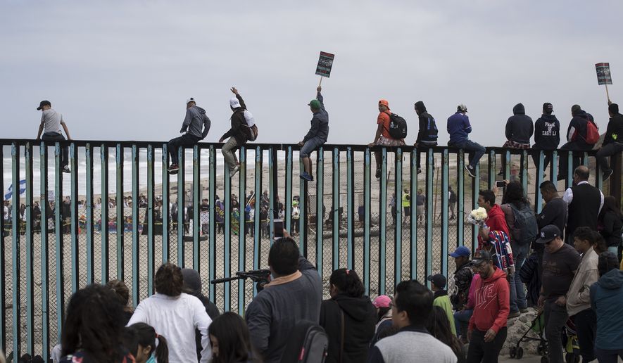 Central American migrants traveling with a caravan gather at the border wall, some sitting on top of it, look toward the U.S. from Mexico during a gathering of migrants living on both sides of the border, on the beach where the border wall ends in the ocean, in Tijuana, Mexico, Sunday, April 29, 2018. U.S. immigration lawyers are telling Central Americans in a caravan of asylum-seekers that traveled through Mexico to the border with San Diego that they face possible separation from their children and detention for many months. They say they want to prepare them for the worst possible outcome. (AP Photo/Hans-Maximo Musielik)