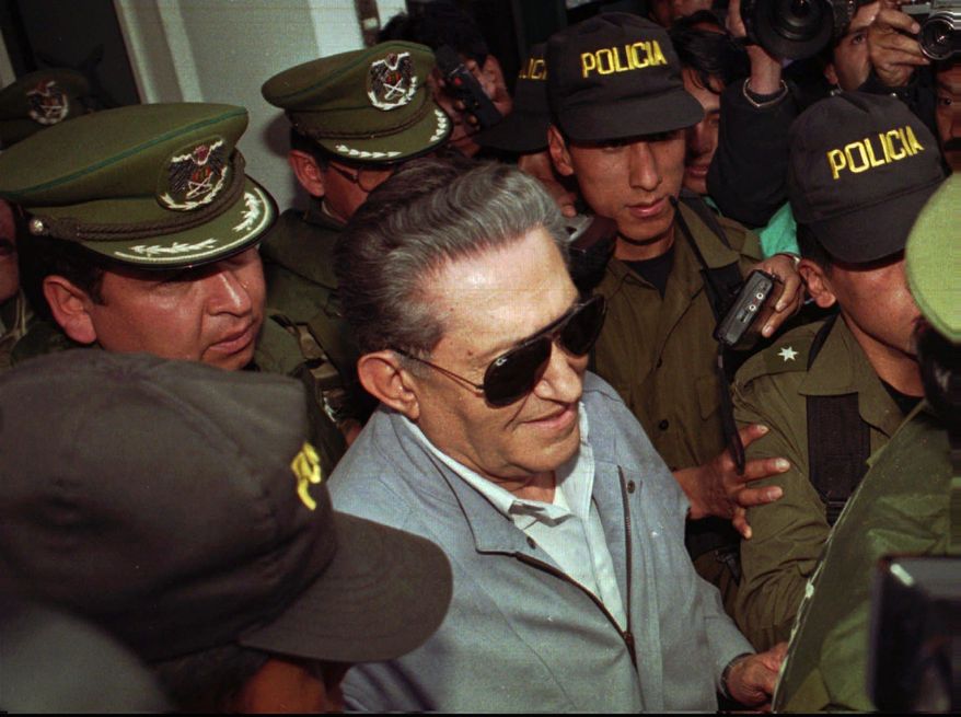 FILE - In this Jan 17 1997 file photo, Bolivia's jailed, ex-dictator Luis Garcia Meza is surrounded by police as he leaves the Copacabana clinic in La Paz, Bolivia after being hospitalized 72 hours for cardiac problems. The former military dictator, who was serving a 30-year prison sentence for a dozen murders carried out during his thirteen months in office from 1980-1981, died on Sunday, April 29, 2018. (AP Photo/Sandra Boulanger, File)