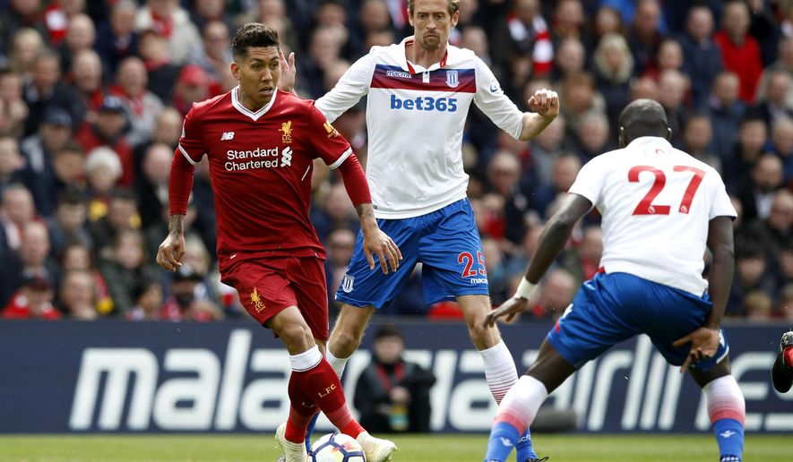 Liverpool&#39;s Roberto Firmino, left, and Stoke City&#39;s Badou Ndiaye, right, face off with Peter Crouch behind, during the English Premier League soccer match at Anfield in Liverpool, England, Saturday April 28, 2018. (Martin Rickett/PA via AP)