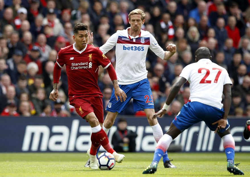 Liverpool&#39;s Roberto Firmino, left, and Stoke City&#39;s Badou Ndiaye, right, face off with Peter Crouch behind, during the English Premier League soccer match at Anfield in Liverpool, England, Saturday April 28, 2018. (Martin Rickett/PA via AP)