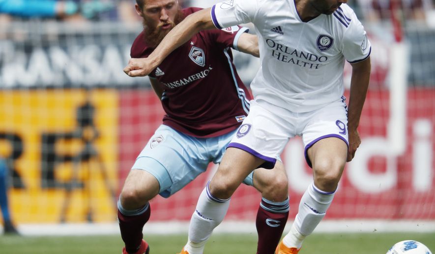 Colorado Rapids midfielder Enzo Martinez, left, battles for control of the ball with Orlando City forward Justin Meram in the first half of an MLS soccer match Sunday, April 29, 2018, in Commerce City, Colo. (AP Photo/David Zalubowski)