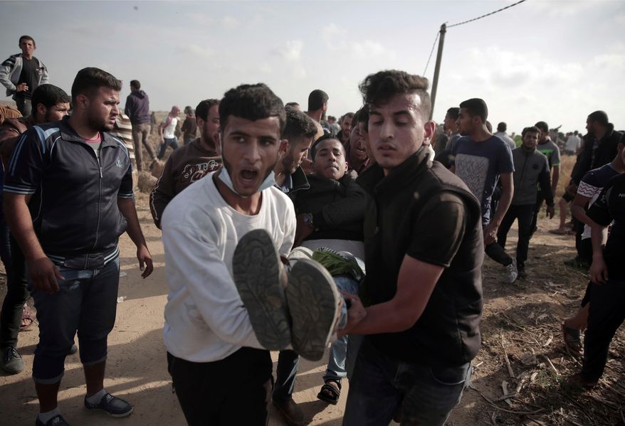 FILE - In this April 27, 2018, file photo, Palestinians carry a wounded man during a protest at the Gaza Strip&#39;s border with Israel. The Supreme Court on Monday, April 30, heard the first legal challenge of the Israeli military&#39;s open-fire rules, after at least 39 Palestinians were killed and more than 1,700 wounded by Israeli fire during mass protests on the Gaza border over the past month. (AP Photo/ Khalil Hamra, File)