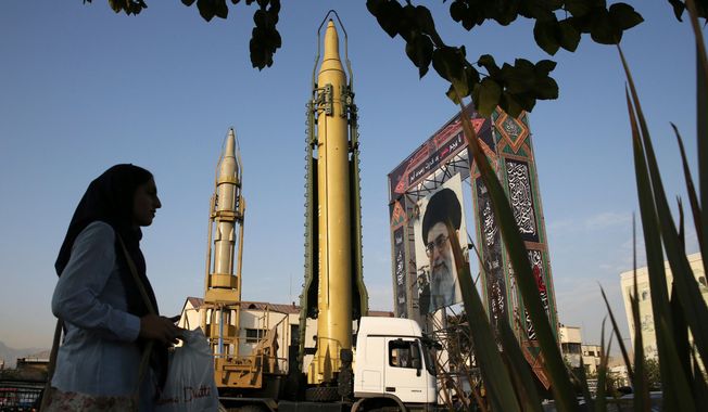 FILE - In this Sept. 24, 2017 file photo, a Ghadr-H missile, center, a solid-fuel surface-to-surface Sejjil missile and a portrait of the Supreme Leader Ayatollah Ali Khamenei are displayed at Baharestan Square in Tehran, Iran. Facing a second suspected Israeli strike killing Iranian forces in Syria, the Islamic Republic has few ways to retaliate as its officials wrestle both domestic unrest at home and the prospects of its nuclear deal collapsing abroad. (AP Photo/Vahid Salemi, File)