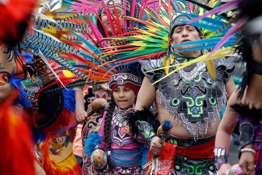 FILE - In this Monday, May 1, 2017, file photo, members of Ce Atl, an Aztec-inspired spiritual and cultural preservation group, dance near the front of a march for worker and immigrant rights at a May Day event in Seattle. The Donald Trump era has been everything that immigrant rights’ groups feared, but while they are taking to the streets again for May Day rallies in solidarity with those around the world, their focus this year is less on a huge turnout on a Tuesday in May than the first Tuesday in November. (AP Photo/Elaine Thompson, File)