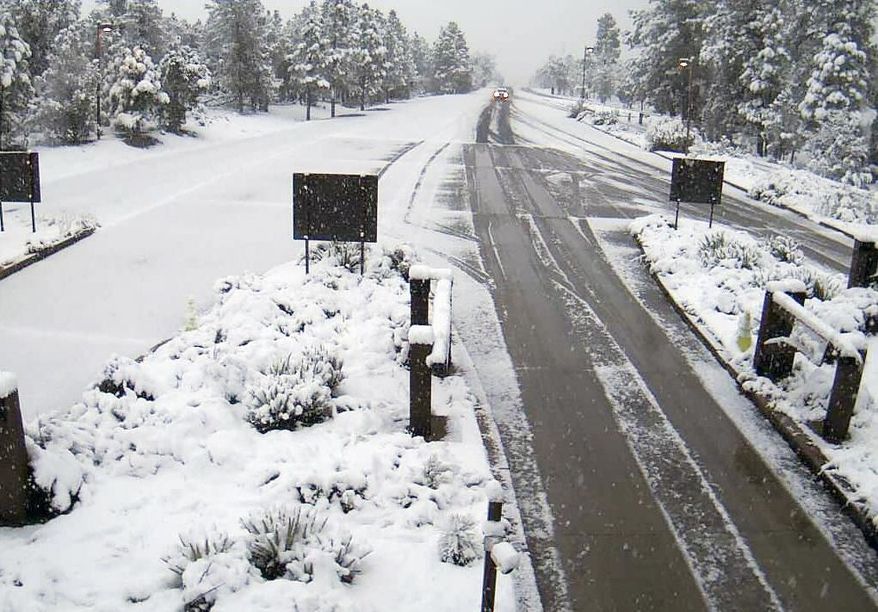 This Tuesday, May 2, 2018 photo provided by the Arizona Department of Transportation from a remote camera at the south gate entrance at the Grand Canyon National Park, Ariz., shows a fresh dusting of snow. Parts of northern and eastern Arizona are getting a late taste of winter weather with snow and rain making for slick roadways Tuesday morning. (Arizona Department of Transportation via AP)