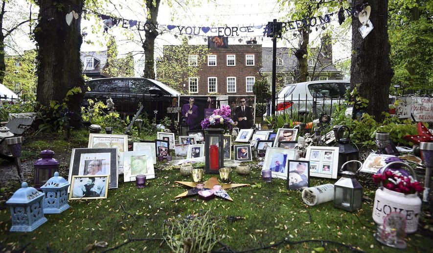 Tributes to George Michael are seen outside his house in Highgate, north London, Wednesday, May 2, 2018. George's Michael's family is asking fans to remove flowers, photos and other tributes left outside the lake singer's two homes. A grassy square across from Michael’s London house is bedecked in bouquets candles, flags and hand-written messages for the singer, who died in December 2016. (Kirsty O'Connor/PA via AP)