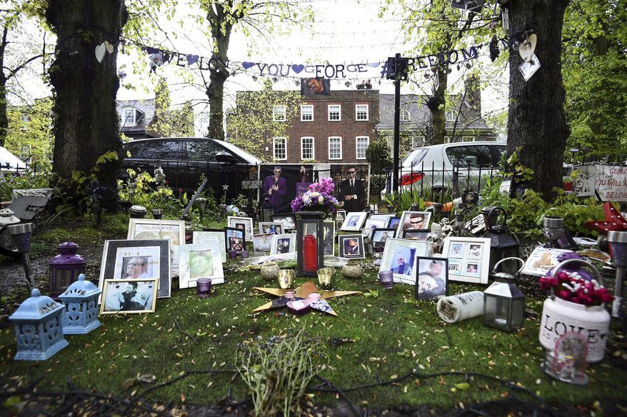 Tributes to George Michael are seen outside his house in Highgate, north London, Wednesday, May 2, 2018. George's Michael's family is asking fans to remove flowers, photos and other tributes left outside the lake singer's two homes. A grassy square across from Michael’s London house is bedecked in bouquets candles, flags and hand-written messages for the singer, who died in December 2016. (Kirsty O'Connor/PA via AP)