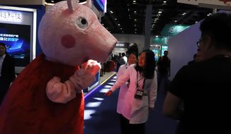 In this April 27, 2018 photo, a woman reacts to a Peppa Pig mascot during the Global Mobile Internet Conference (GMIC) in Beijing, China. The cherubic British cartoon character, Peppa Pig, has become an unlikely target of China&#39;s censors as online fans use her porcine likeness in sardonic memes and &amp;quot;gangster&amp;quot; catchphrases. (AP Photo/Ng Han Guan)