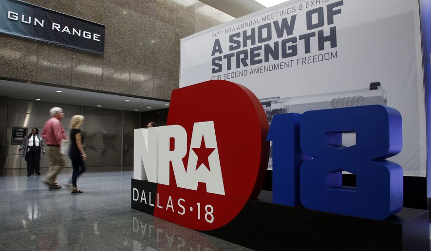 People walk by NRA convention signage in the Kay Bailey Hutchison Convention Center in Dallas, Thursday, May 3, 2018. The convention is scheduled to go through Sunday. (AP Photo/Sue Ogrocki)