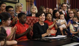 Iowa Gov. Kim Reynolds, center, reacts after signing a six-week abortion ban bill into law during a ceremony in her formal office, Friday, May 4, 2018, in Des Moines, Iowa. The bill gives Iowa the strictest abortion restrictions in the nation, setting the state up for a lengthy court challenge. (AP Photo/Charlie Neibergall) ** FILE **